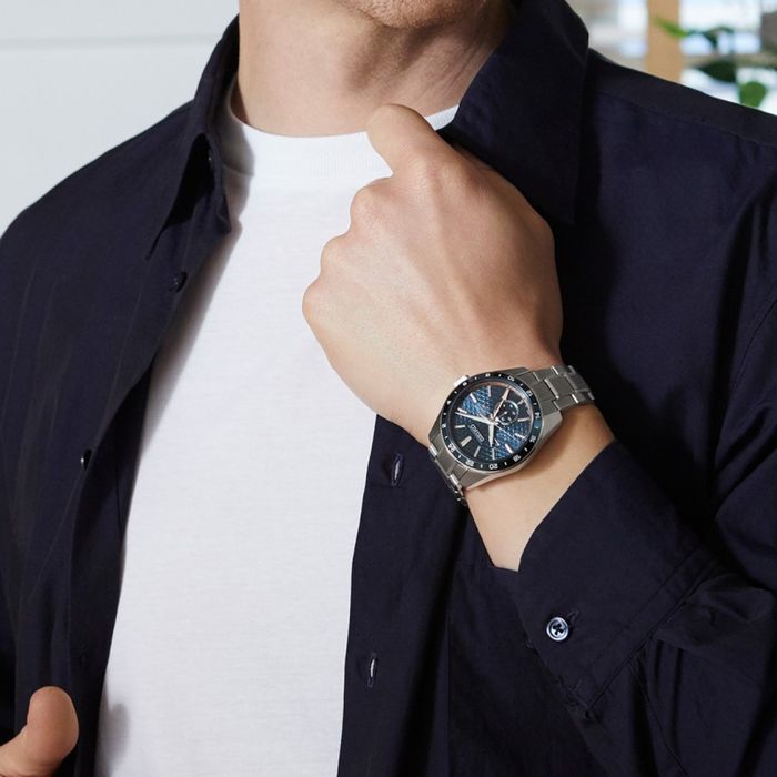 Pulso masculino com relógio Seiko Presage em aço inoxidável prateado, automático, de mostrador azul.
