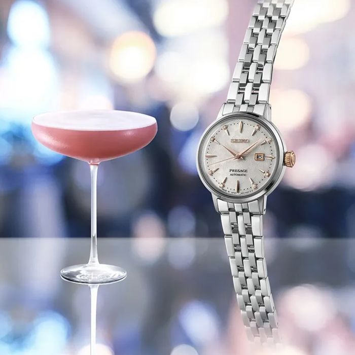 Imagem de relógio feminino Seiko Presage, bracelete e caixa em aço prateado com cocktail ao lado.