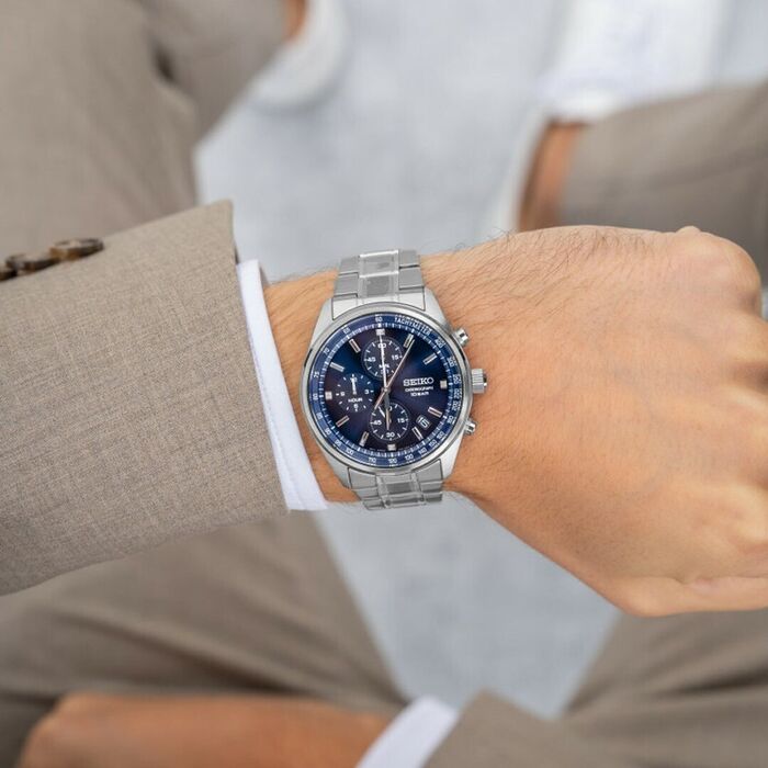Pulso masculino com relógio Seiko Neo Sport, de bracelete e caixa em aço, mostrador azul cronógrafo.