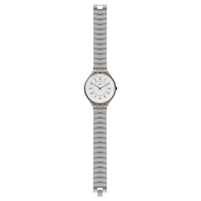 Vista de frente de um relógio analógico prateado da Swatch, alongado, com um mostrador branco.
