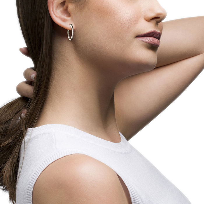Modelo feminino com uma argola Unike em prata banhada a ouro rosa com cravação de zircónias pretas.