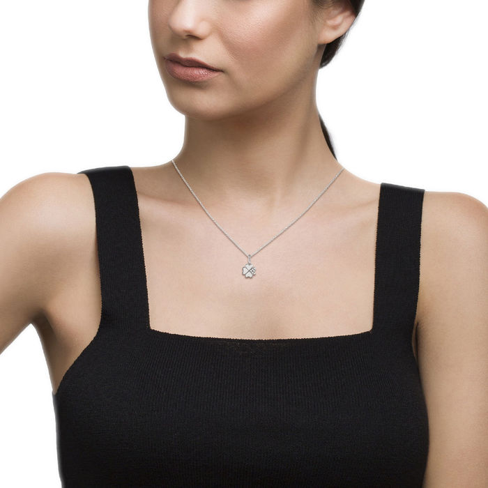 Modelo com um colar prateado da Unike com pendente de um trevo de quatro folhas, uma com pedras.