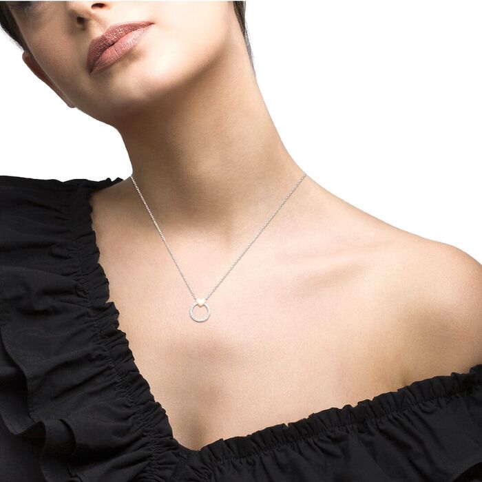 Modelo com colar Unike de pendente circular com zircónias e um coração no topo banhado a ouro rosa.
