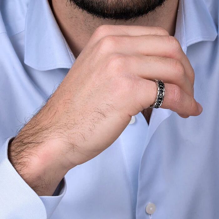 Modelo masculino de camisa azul com o anel da Albert M. prateado no seu dedo mindinho.