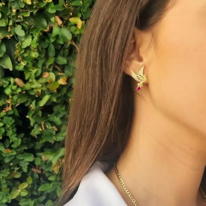 Modelo feminino com um brinco dourado Portugal Jewels em forma de pombas com uma zircónia rosa.