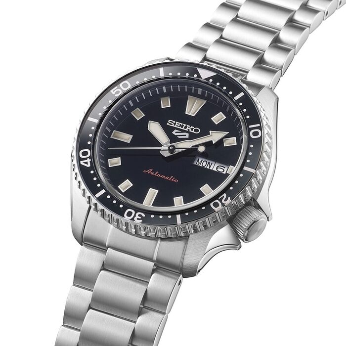 Vista aproximada de relógio Seiko prateado de bisel e mostrador preto com calendário nas 3 horas.