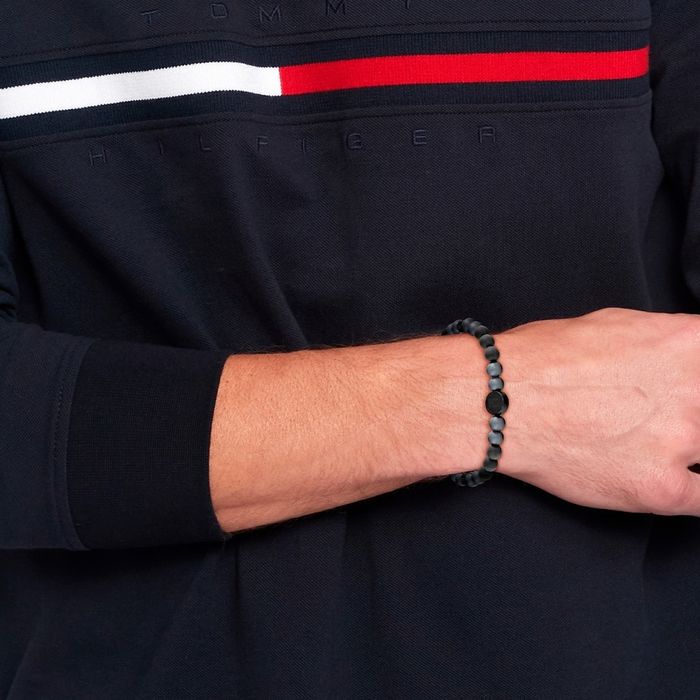 Pulseira Tommy Hilfiger para homem com pérolas pretas e cinzentas, no pulso do modelo.