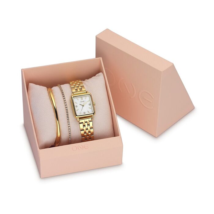 Caixa rosa com relógio dourado ONE de caixa quadrada e duas pulseiras sobre almofada.