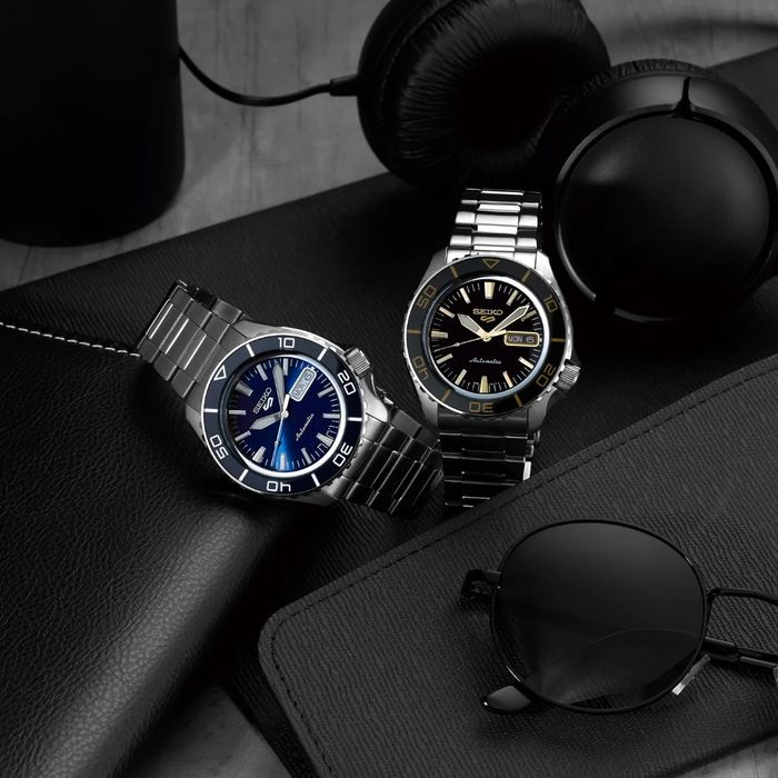 Dois relógios de pulso prateados com bracelete metal e caixa redonda, com mostrador azul e preto