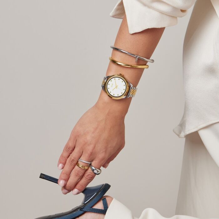 Pulso feminino a segurar salto, com smartwatch One prateado com bracelete bicolor e duas escravas