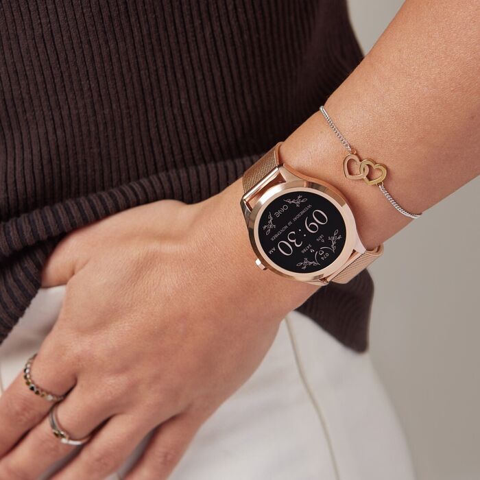 Pulso feminino a usar smartwatch da One e acessórios, modelo com bracelete e caixa de tom rose gold.