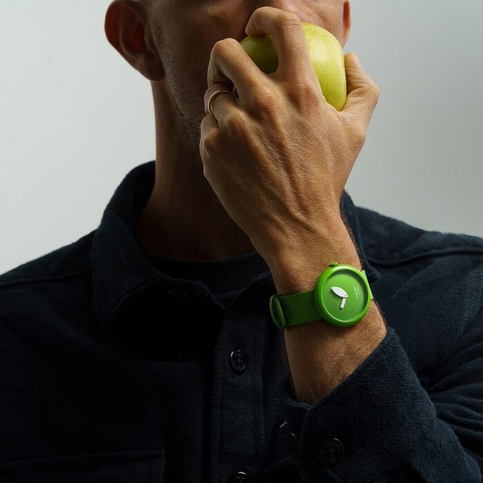 Homem com maça a usar relógio Cauny bracelete verde, caixa verde e ponteiros em forma folha de maça