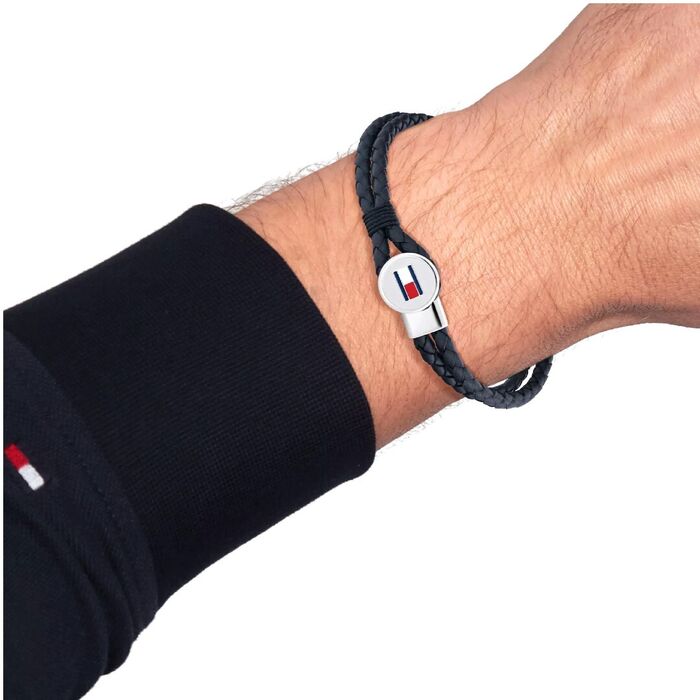 Pulseira Tommy em couro genuíno azul entrelaçado com aço no fecho, no pulso do modelo.