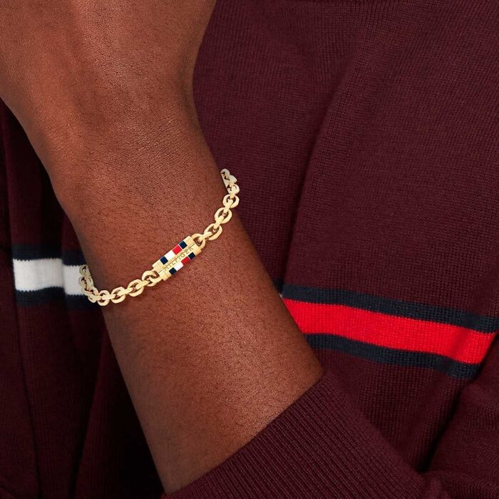 Pulseira Tommy em aço inoxidável dourado no pulso do modelo.