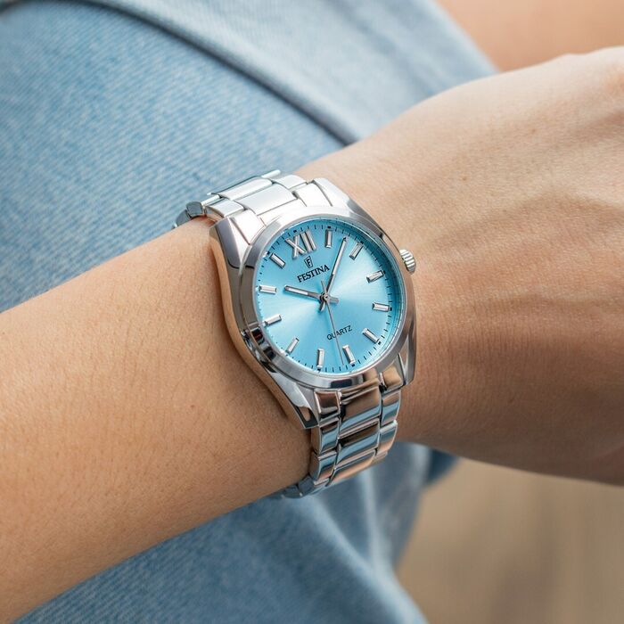 Pulso feminino com relógio Festina de bracelete e caixa prateada com mostrador azul formato redondo