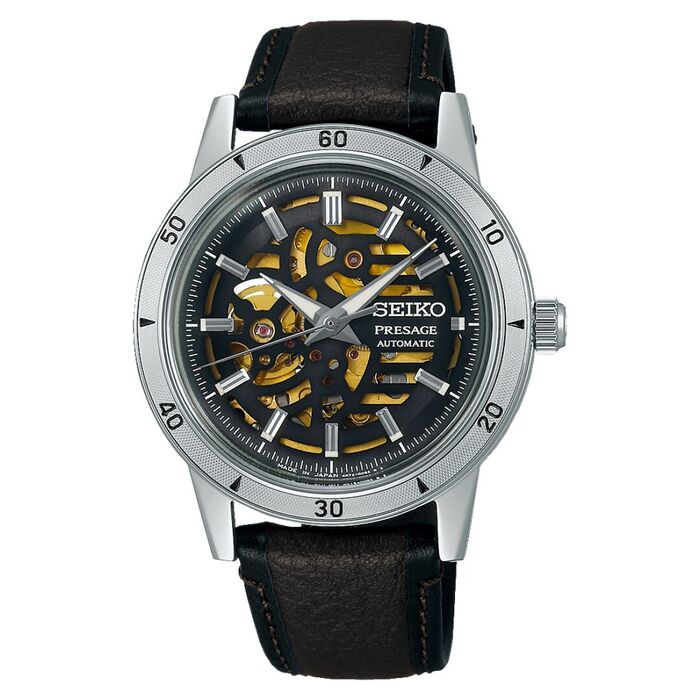 Relógio de bracelete castanha em pele e mostrador preto com recortes que tornam visível o interior.