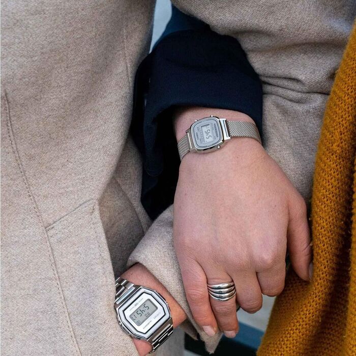 Mãos entrelaçadas masculina e feminina com dois relógios Casio prateados de diferentes dimensões