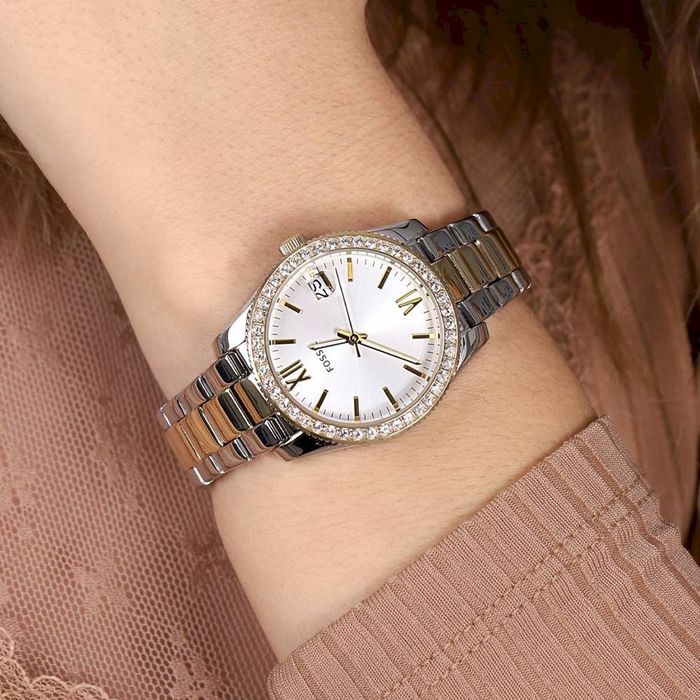 Relógio feminino da fossil com bracelete bicolor com mostrador branco, no pulso.
