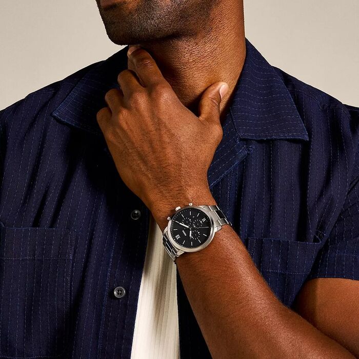 Relógio Fossil para homem com bracelete em aço prateado e mostrador preto, com cronógrafo, no pulso.