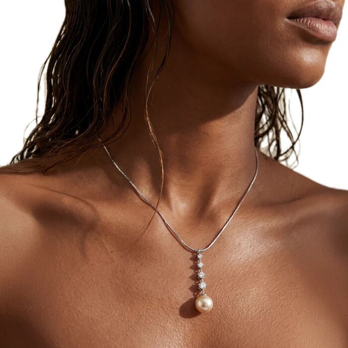 Modelo com um colar prateado Majorica de pendente vertical com uma fila de zircónias e uma pérola.