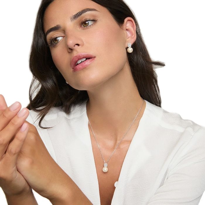 Modelo feminino com uns brincos Majorica prateados com zircónias sobre uma pérola branca de cultivo.