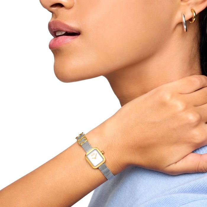 Pulso de mulher com relógio TOUS quadrado bicolor, bracelete malha prateada e pendente urso dourado