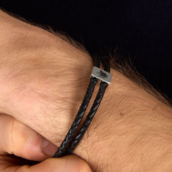 Pulseira preta trançada dupla com fecho metálico retangular e símbolo gravado no pulso