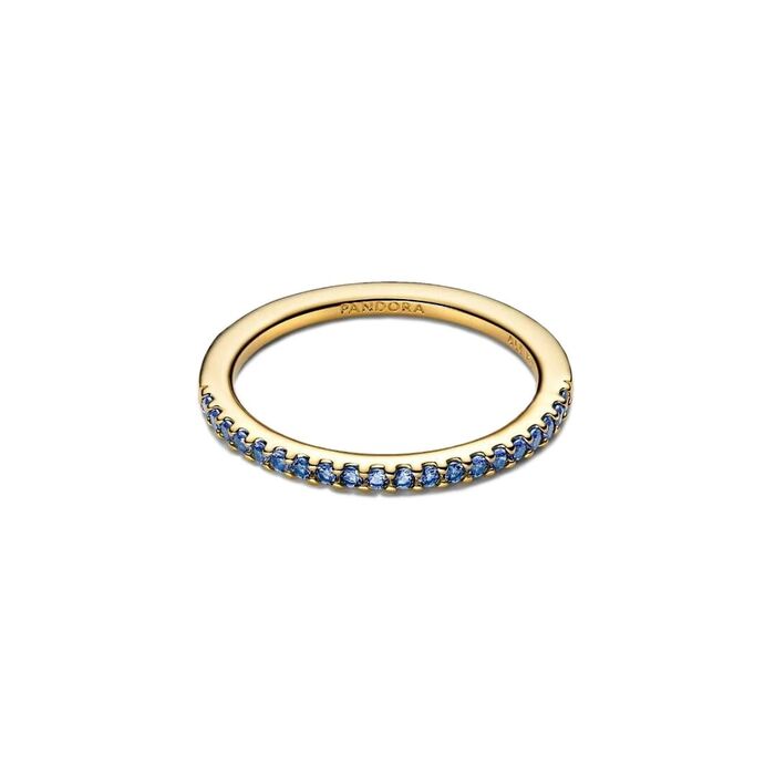 Anel feminino dourado Pandora, pousado, com zircónias azuis cravadas em metade do aro.
