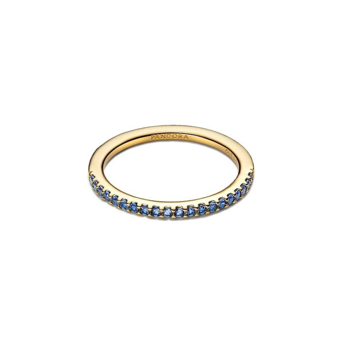Anel feminino dourado Pandora, pousado, com zircónias azuis cravadas em metade do aro.