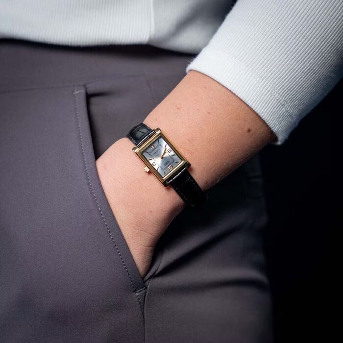 Relógio Casio vintage com caixa retângular dourada, e bracelete em pele preta, no pulso.