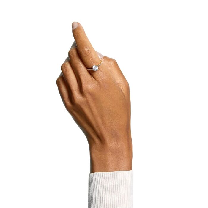 Anel Swarovski feminino de cor dourada com cristais Swarovski, tipo solitário, no dedo da modelo.