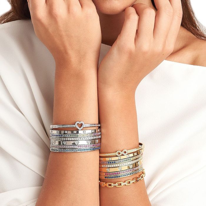 Modelo feminino com pulseiras Nomination com pedras, num braço em prateados e no outro em dourados.