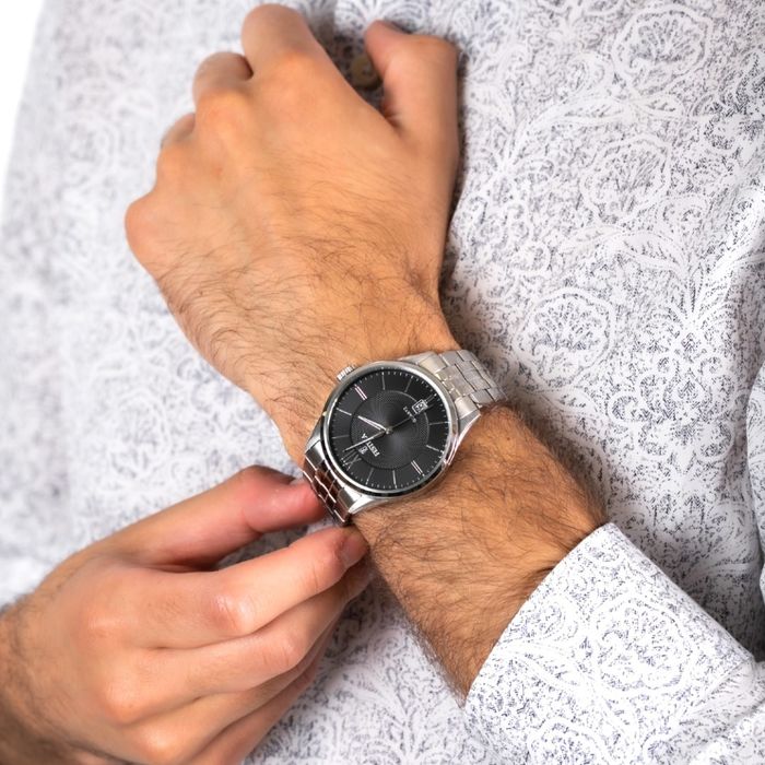 Modelo com relógio prateado Festina de mostrador analógico preto e com calendário nas seis horas.
