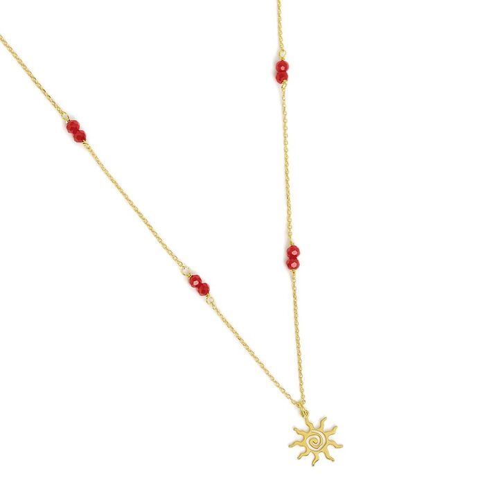 Colar dourado Eugénio Campos pousado com contas vermelhas na malha e um pendente em forma de sol.