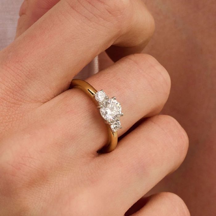 Anel TI SENTO bicolor prateado e dourado com duas zircónias no meio grande e duas pequenas, no dedo.