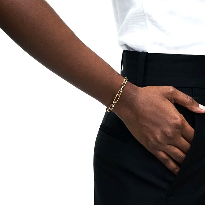 Modelo com uma pulseira dourada Pandora com uma malha de elos de diferentes tamanhos entrelaçados.