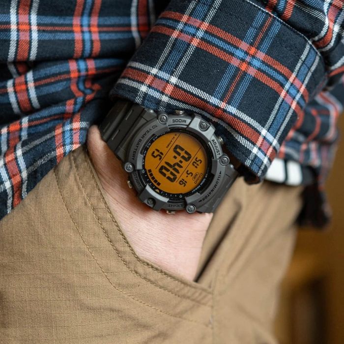 Relógio digital com mostrador laranja com cronógrafo, calendário e bracelete em resina, no pulso.