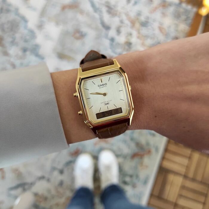 Relógio Casio mostrador dourado, bracelete pele castanha e mostrador digital/analógico, no pulso.