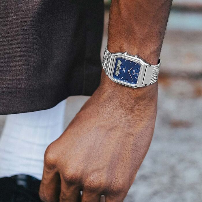 Relógio vintage Casio analógico e digital com bracelete em malha de aço e mostrador azul, no pulso.