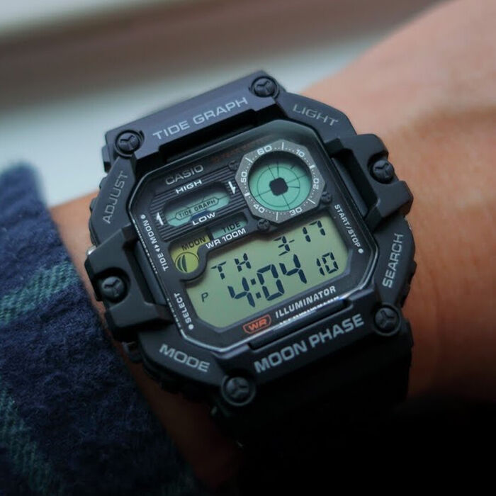 Relógio digital Casio preto no pulso, visor LCD com gráfico de marés e fase lunar