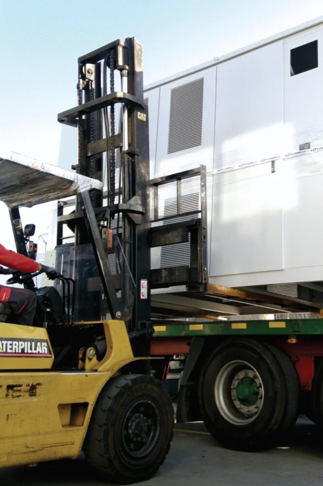 Electrical cabinet for a photovoltaic park being loaded onto a truck by a forklift, ready for installation, showcasing industrial handling and logistics.