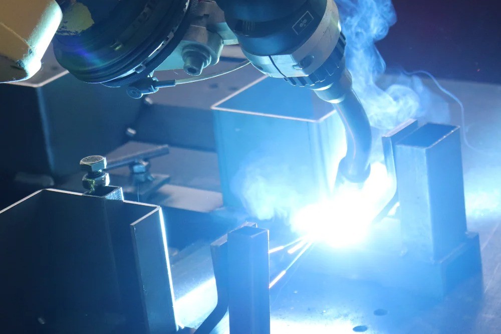 Fanuc robotic welding arm performing welding on a metal part at V Laser On in Portugal