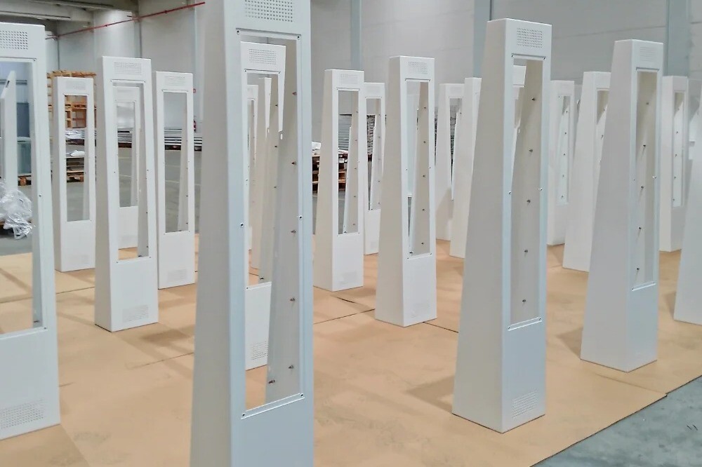 Assembly line with metal housings of digital displays being assembled, showcasing precision manufacturing and production workflow.