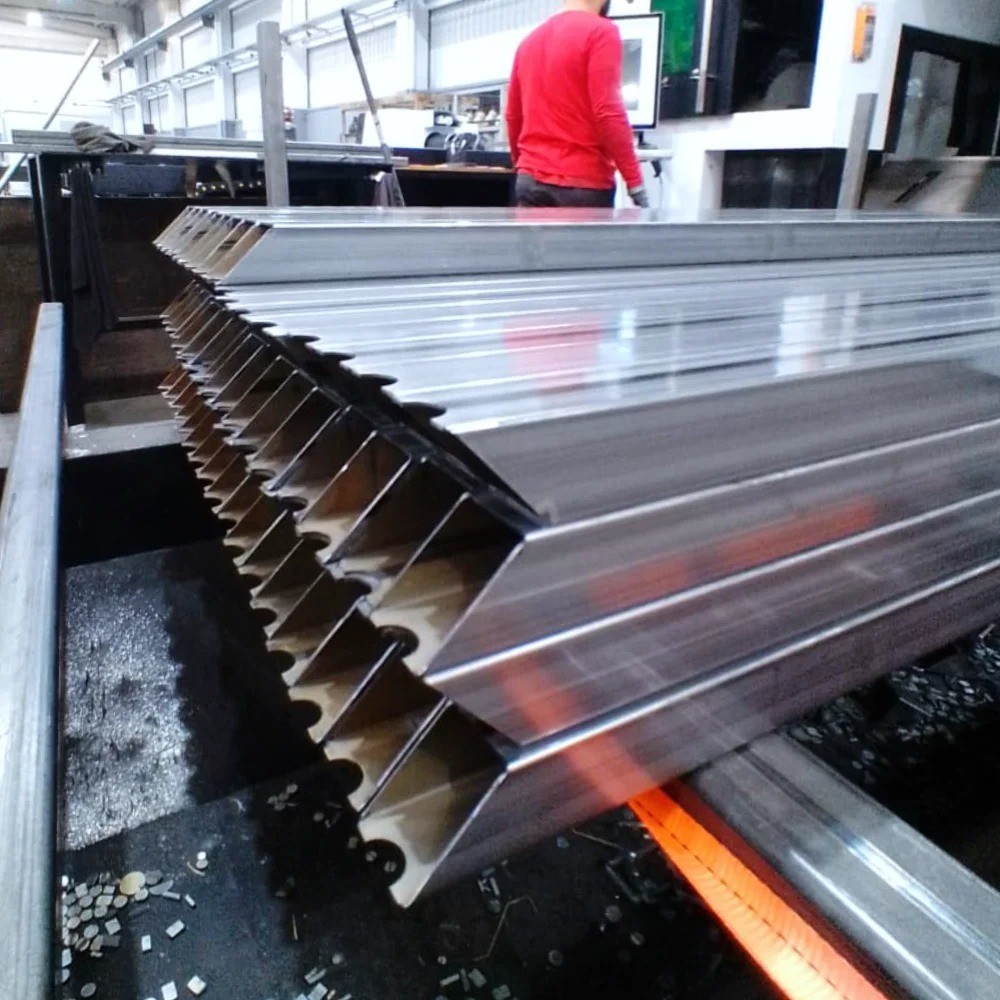 Worker operating 3D laser cutting equipment for tubes and profiles, with machine and operator visible in the background at V Laser On in Portugal