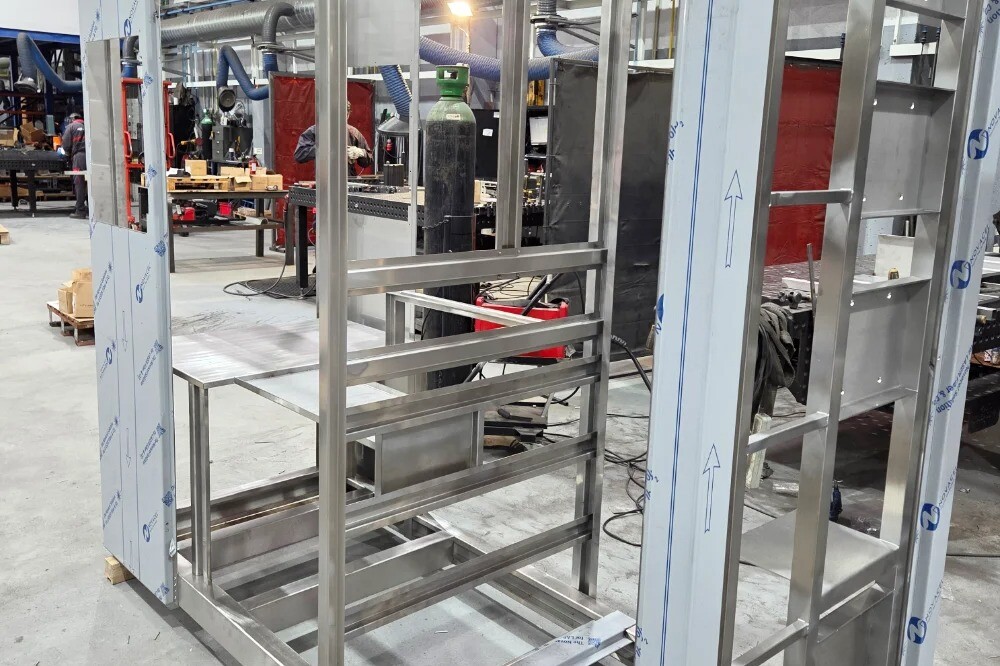 Custom stainless steel and aluminum cabinet under construction in the welding hall of an industrial facility, showcasing precision metal fabrication and assembly