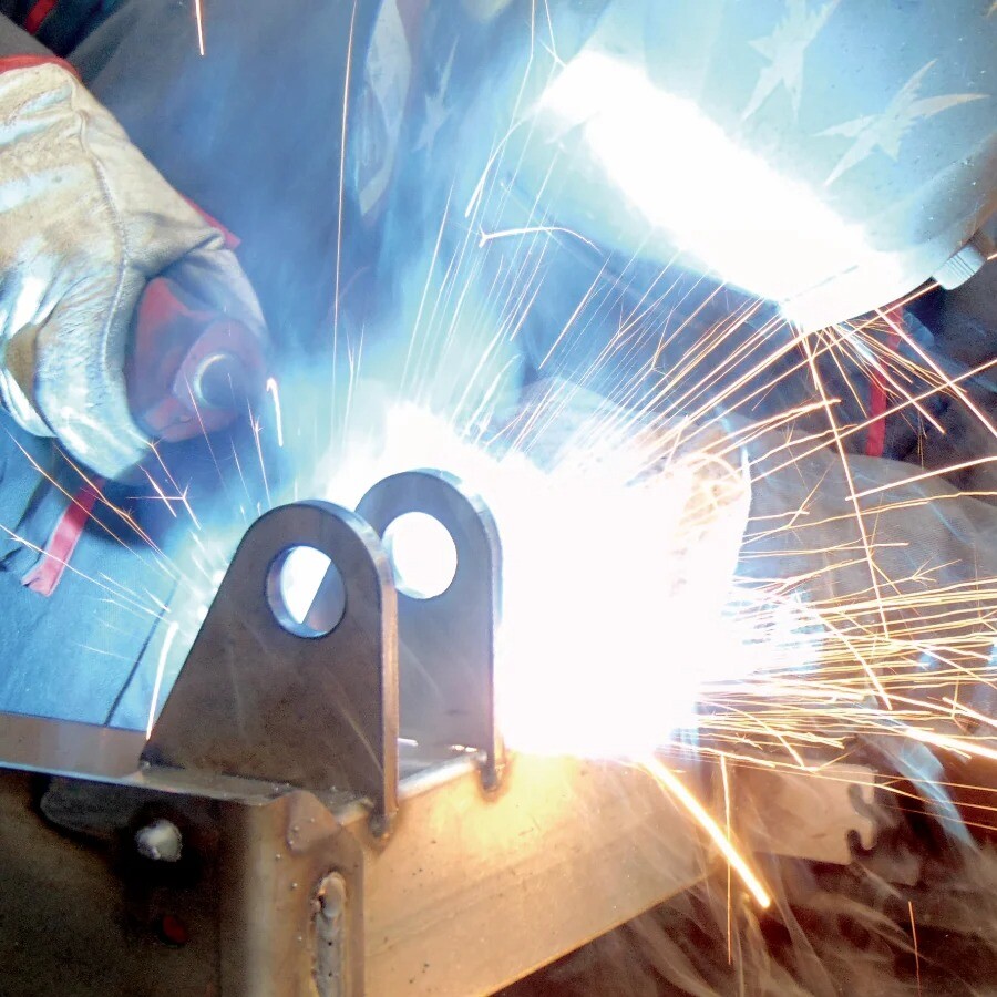 Welder performing manual steel welding with sparks flying, wearing protective helmet, showcasing precision craftsmanship at V Laser On in Portugal