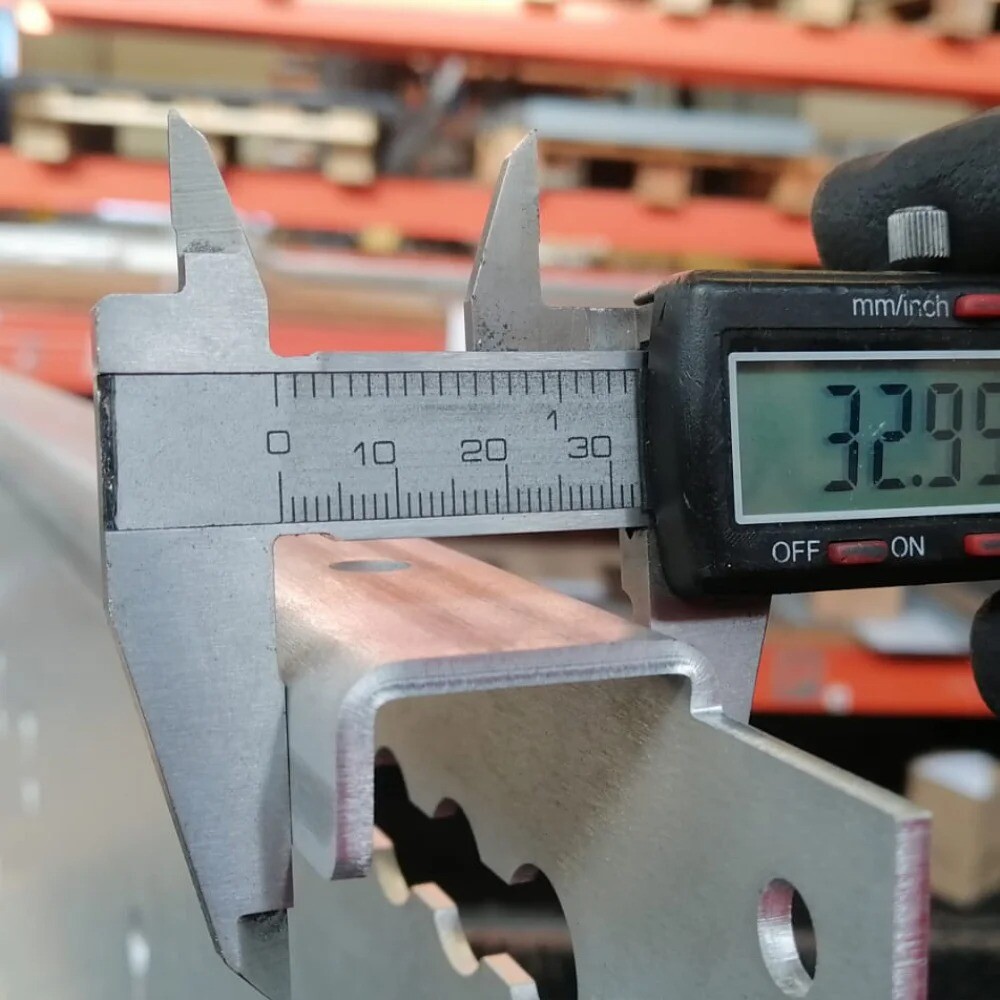 Employee performing dimensional inspection of a metal component using a caliper, ensuring precision and compliance with specifications at V Laser On Portugal