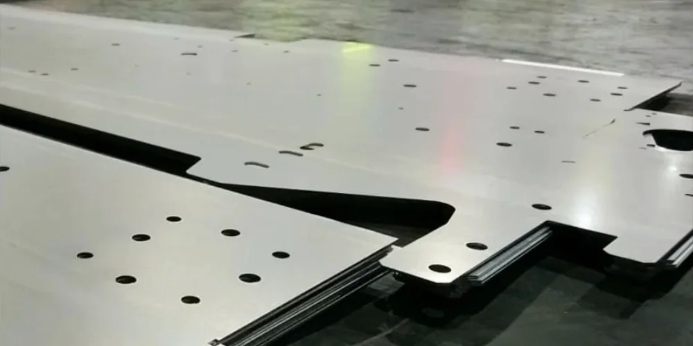 Laser-cut stainless steel sheets at V Laser On workshop in Porto Portugal, showcasing precision industrial laser cutting for machinery components