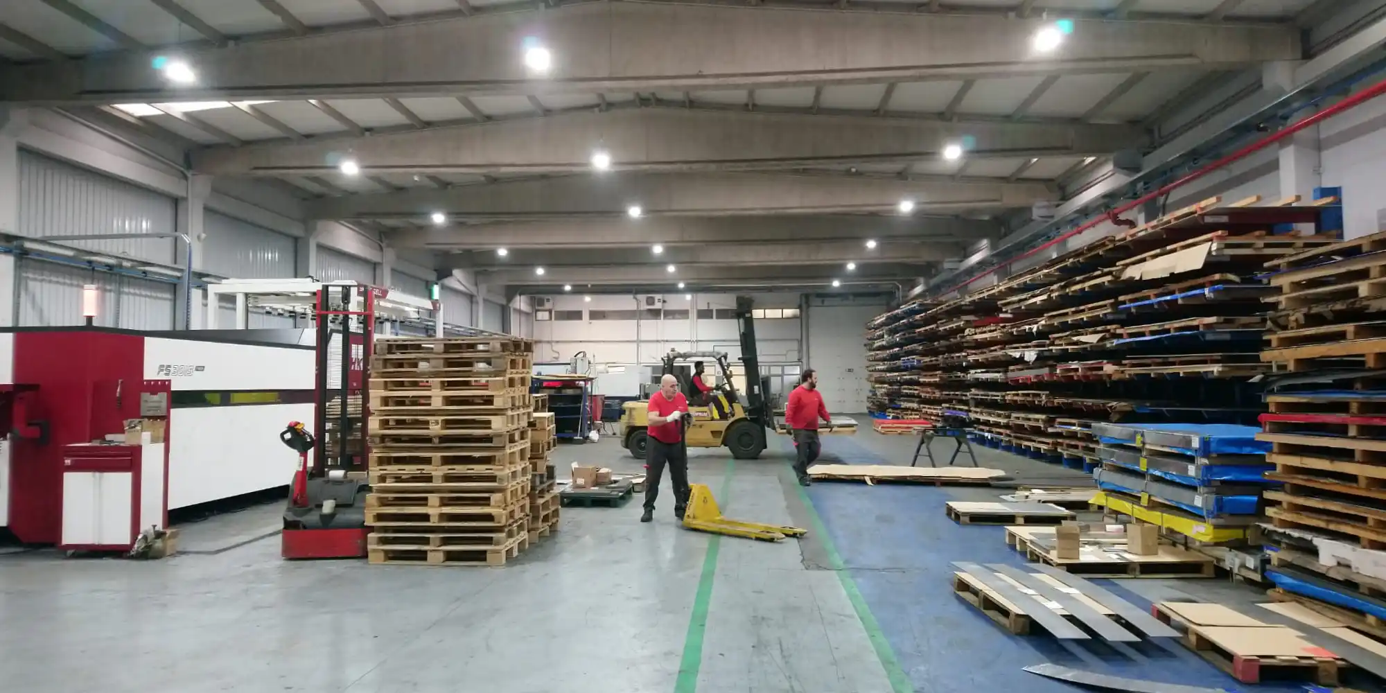 V Laser On exclusive laser cutting facility in Porto, Portugal showing the team, in-house metal sheet stock, and two laser cutting machines for precision industrial fabrication